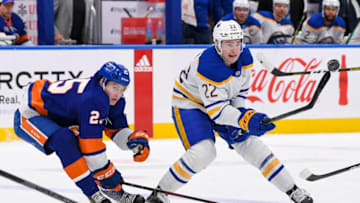 Mar 7, 2023; Elmont, New York, USA; Buffalo Sabres right wing Jack Quinn (22) attempts to control a loose puck defended by New York Islanders defenseman Sebastian Aho (25) during the first period at UBS Arena. Mandatory Credit: Dennis Schneidler-USA TODAY Sports