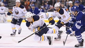 Mar 7, 2016; Toronto, Ontario, CAN; Buffalo Sabres center Jack Eichel (15) is tripped up as he carries the puck by Toronto Maple Leafs defenseman Morgan Rielly (44) at Air Canada Centre. The Sabres beat the Maple Leafs 4-3 in a shootout. Mandatory Credit: Tom Szczerbowski-USA TODAY Sports