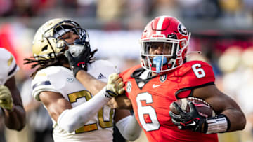 ATHENS, GA - NOVEMBER 26: Kenny McIntosh #6 of the Georgia Bulldogs tries to evade a tackle by LaMiles Brooks #20 of the Georgia Tech Yellow Jackets during a game between Georgia Tech Yellow Jackets and Georgia Bulldogs at Sanford Stadium on November 26, 2022 in Athens, Georgia. (Photo by Steve Limentani/ISI Photos/Getty Images)