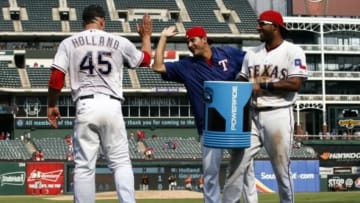 Aug 30, 2015; Arlington, TX, USA; Texas Rangers starting pitcher Derek Holland (45) celebrates with teammates Martin Perez (center) and Elvis Andrus following his complete game three-hit shutout over the Baltimore Orioles following a ballgame at Globe Life Park in Arlington. The Rangers won 6-0. Mandatory Credit: Jim Cowsert-USA TODAY Sports