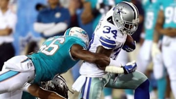 Aug 4, 2013; Canton, OH, USA; Dallas Cowboys running back Phillip Tanner (34) runs through the tackle attempt of Miami Dolphins linebacker Jonathan Freeny (56) during the second quarter at Fawcett Stadium. Mandatory Credit: Ron Schwane-USA TODAY Sports