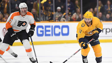 Mar 27, 2022; Nashville, Tennessee, USA; Nashville Predators center Luke Kunin (11) skates the puck into the offensive zone past Philadelphia Flyers center Zack MacEwen (17) during the third period at Bridgestone Arena. Mandatory Credit: Christopher Hanewinckel-USA TODAY Sports
