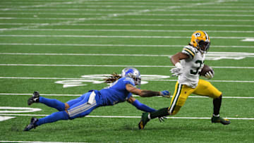 DETROIT, MICHIGAN - DECEMBER 13: Mike Ford #38 of the Detroit Lions attempts to tackle Aaron Jones #33 of the Green Bay Packers during the second half at Ford Field on December 13, 2020 in Detroit, Michigan. (Photo by Nic Antaya/Getty Images)