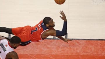Feb 27, 2014; Toronto, Ontario, CAN; Washington Wizards guard John Wall (10) shoots as he is tripped up on a fould by Toronto Raptors forward Amir Johnson (15) at Air Canada Centre. Mandatory Credit: Tom Szczerbowski-USA TODAY Sports