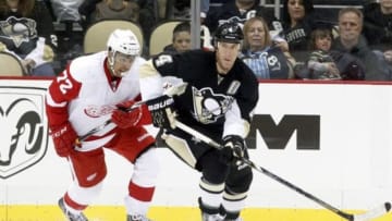 Sep 22, 2014; Pittsburgh, PA, USA; Pittsburgh Penguins defenseman Rob Scuderi (4) moves the puck as Detroit Red Wings center Andreas Athanasiou (72) chases during the third period at the CONSOL Energy Center. The Red Wings won 2-1. Mandatory Credit: Charles LeClaire-USA TODAY Sports