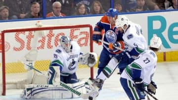 Apr 12, 2014; Edmonton, Alberta, CAN; Vancouver Canucks goalie Jacob Markstrom (35) makes a save and Vancouver Canucks defenseman Jason Garrison (5) fights with Edmonton Oilers left wing Ryan Smyth (94) for position in front of the net in the second period at Rexall Place. Mandatory Credit: Chris Austin-USA TODAY Sports