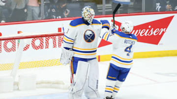 Dec 14, 2021; Winnipeg, Manitoba, CAN; Buffalo Sabres goalie Ukko Pekka Luukkonen (1) is congratulated by Buffalo Sabres defenseman Will Butcher (4) on their win against the Winnipeg Jets at the end of the third period at Canada Life Centre. Mandatory Credit: Terrence Lee-USA TODAY Sports