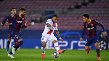 Kylian Mbappe of Paris Saint-Germain takes a shot whilst under pressure from Gerard Pique and Sergino Dest of FC Barcelona. (Photo by David Ramos/Getty Images)