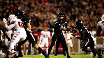 Cincinnati Bearcats quarterback Desmond Ridder hands the ball off to running back Jerome Ford against the Temple Owls. The Enquirer.