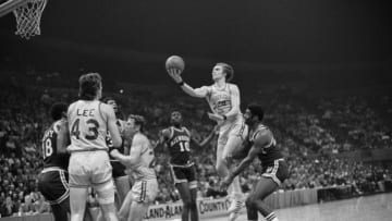 Rick Barry (24) of the San Francisco Warriors is shown leaping through the air past Oscar Robertson (4) of the Milwaukee Bucks as he shoots for the basket.