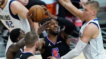 May 25, 2021; Los Angeles, California, USA; LA Clippers guard Paul George (center) is defended by Dallas Mavericks forward Dorian Finney-Smith (left) and center Kristaps Porzingis (right) during the third quarter of game two in the first round of the 2021 NBA Playoffs at Staples Center. Mandatory Credit: Robert Hanashiro-USA TODAY Sports