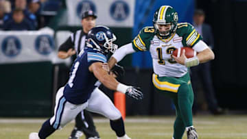TORONTO, ON - OCTOBER 4: Mike Reilly #13 of the Edmonton Eskimos runs the ball as Shea Emry #41 of the Toronto Argonauts closes in to make a tackle during their game at Rogers Centre on October 4, 2014 in Toronto, Canada. (Photo by Dave Sandford/Getty Images)