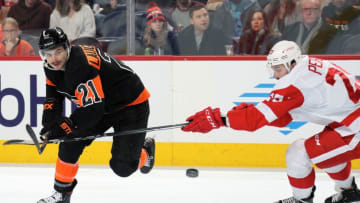 PHILADELPHIA, PA - NOVEMBER 29: Scott Laughton #21 of the Philadelphia Flyers battles for the airborne puck against Brendan Perlini #29 of the Detroit Red Wings on November 29, 2019 at the Wells Fargo Center in Philadelphia, Pennsylvania. (Photo by Len Redkoles/NHLI via Getty Images)