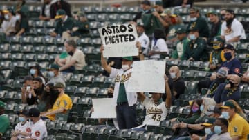 OAKLAND, CALIFORNIA - APRIL 01: Oakland Athletics fans hold up signs about the Houston Astros cheating during their Opening Day game at RingCentral Coliseum on April 01, 2021 in Oakland, California. (Photo by Ezra Shaw/Getty Images)