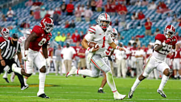 Jan 11, 2021; Miami Gardens, Florida, USA; Ohio State Buckeyes quarterback Justin Fields (1) runs the ball against Alabama Crimson Tide linebacker Christian Harris (8) and defensive back DeMarcco Hellams (29) during the third quarter in the 2021 College Football Playoff National Championship Game. Mandatory Credit: Kim Klement-USA TODAY Sports