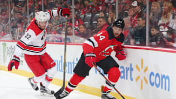 NEWARK, NJ - DECEMBER 29: Brett Pesce #22 of the Carolina Hurricanes and Miles Wood #44 of the New Jersey Devils skate after a loose puck during the third period at the Prudential Center on December 29, 2018 in Newark, New Jersey. The Devils defeated the Hurricanes 2-0. (Photo by Andy Marlin/NHLI via Getty Images)