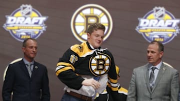 Jun 24, 2016; Buffalo, NY, USA; Trent Frederic puts on a team jersey after being selected as the number twenty-nine overall draft pick by the Boston Bruins in the first round of the 2016 NHL Draft at the First Niagra Center. Mandatory Credit: Timothy T. Ludwig-USA TODAY Sports