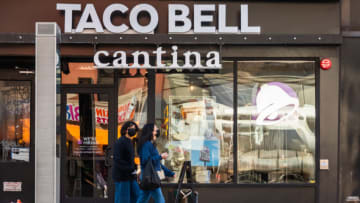 NEW YORK, NEW YORK - MARCH 21: Two people wearing masks walk by a Taco Bell Cantina in Chelsea on March 21, 2021 in New York City. After undergoing various shutdown orders for the past 12 months the city is currently in phase 4 of its reopening plan, allowing for the reopening of low-risk outdoor activities, movie and television productions, indoor dining as well as the opening of movie theaters, all with capacity restrictions. (Photo by Noam Galai/Getty Images)