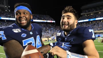CHAPEL HILL, NORTH CAROLINA - OCTOBER 26: Teammates Jordan Tucker #74 and Sam Howell #7 of the North Carolina Tar Heels celebrate after defeating the Duke Blue Devils 20-17 at Kenan Stadium on October 26, 2019 in Chapel Hill, North Carolina. (Photo by Streeter Lecka/Getty Images)