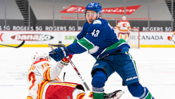 VANCOUVER, BC - FEBRUARY 13: Quinn Hughes #43 of the Vancouver Canucks knocks Johnny Gaudreau #13 of the Calgary Flames to the ice while chasing after a loose puck during NHL hockey action at Rogers Arena on February 13, 2021 in Vancouver, Canada. (Photo by Rich Lam/Getty Images)