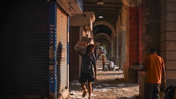 MUMBAI, INDIA - APRIL 29: A man carries a stack of newspapers down a near-deserted alley during a lockdown imposed to try and contain the spread of Covid-19 on April 29, 2021 in Mumbai, India. With recorded cases crossing 380,000 a day and 3000 deaths in the last 24 hours, India has more than 2 million active cases of Covid-19, the second-highest number in the world after the U.S. A new wave of the pandemic has totally overwhelmed the country's healthcare services and has caused crematoriums to operate day and night as the number of victims continues to spiral out of control. (Photo by Fariha Farooqui/Getty Images)
