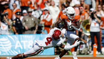 DALLAS, TEXAS - OCTOBER 09: Xavier Worthy #8 of the Texas Longhorns gives a stiff arm to Jaden Davis #4 of the Oklahoma Sooners and runs for a touchdown in the first quarter during the 2021 AT&T Red River Showdown at Cotton Bowl on October 09, 2021 in Dallas, Texas. (Photo by Tim Warner/Getty Images)