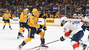 Feb 18, 2023; Nashville, Tennessee, USA; Nashville Predators center Philip Tomasino (26) shoots the puck against Florida Panthers defenseman Radko Gudas (7) during the first period at Bridgestone Arena. Mandatory Credit: Christopher Hanewinckel-USA TODAY Sports