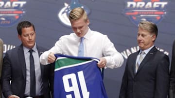 Jun 24, 2016; Buffalo, NY, USA; Olli Juolevi puts on a team jersey after being selected as the number five overall draft pick by the Vancouver Canucks in the first round of the 2016 NHL Draft at the First Niagra Center. Mandatory Credit: Timothy T. Ludwig-USA TODAY Sports