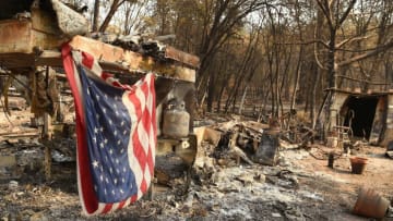 An American flag hangs at a burned out mobile home park in Paradise, California on November 18, 2018. - The family lost a home in the same spot to a fire 10 years prior. (Photo by Josh Edelson / AFP) (Photo credit should read JOSH EDELSON/AFP/Getty Images)