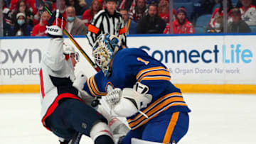 BUFFALO, NY - DECEMBER 11: T.J. Oshie #77 of the Washington Capitals crashes into Ukko-Pekka Luukkonen #1 of the Buffalo Sabres during the first period at KeyBank Center on December 11, 2021 in Buffalo, New York. (Photo by Kevin Hoffman/Getty Images)