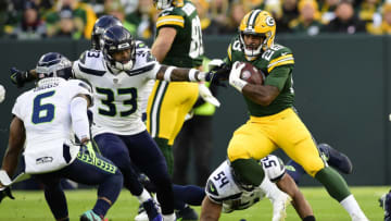 GREEN BAY, WISCONSIN - NOVEMBER 14: A.J. Dillon #28 of the Green Bay Packers carries the ball against Jamal Adams #33 and Quandre Diggs #6 of the Seattle Seahawks during the first quarter at Lambeau Field on November 14, 2021 in Green Bay, Wisconsin. (Photo by Patrick McDermott/Getty Images)