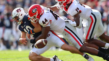 AUBURN, ALABAMA - OCTOBER 09: Bo Nix #10 of the Auburn Tigers fumbles the ball as he is tackled by Travon Walker #44 and Adam Anderson #19 of the Georgia Bulldogs during the first half at Jordan-Hare Stadium on October 09, 2021 in Auburn, Alabama . After a review, the play was overturned and ruled as intentional grounding by Nix. (Photo by Kevin C. Cox/Getty Images)