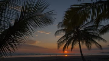 COSTA RICA - 2009/12/14: A sunset over the Pacific Ocean with silhouetted coconut palm trees on a beach at the Monterey Del Mar Hotel near Jaco in Costa Rica. (Photo by Wolfgang Kaehler/LightRocket via Getty Images)