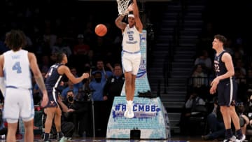 Mar 10, 2022; Brooklyn, NY, USA; North Carolina Tar Heels forward Armando Bacot (5) hangs on the rim after dunking against Virginia Cavaliers guard Armaan Franklin (4) and center Francisco Caffaro (22) during the second half at Barclays Center. Mandatory Credit: Brad Penner-USA TODAY Sports