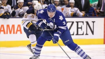 Dec 27, 2013; Toronto, Ontario, CAN; Toronto Maple Leafs defenseman Dion Phaneuf (3) goes to the net with the puck as he is checked by Buffalo Sabres left wing Matt Moulson (26) at Air Canada Centre. Mandatory Credit: Tom Szczerbowski-USA TODAY Sports