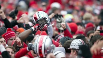 November 24, 2012; Columbus, OH, USA; A player for the Ohio State Buckeyes holds his helmet in the air surrounded by fans on the field after the game against the Michigan Wolverines at Ohio Stadium. Ohio State won the game 26-21. Mandatory Credit: Greg Bartram-USA TODAY Sports