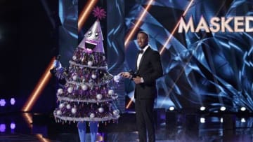 THE MASKED SINGER: L-R: The Tree with host Nick Cannon in the “Clash of the Masks” episode of THE MASKED SINGER airing Wednesday, Dec. 4 (8:00-9:01 PM ET/PT) on FOX. © 2019 FOX MEDIA LLC. CR: Michael Becker / FOX.