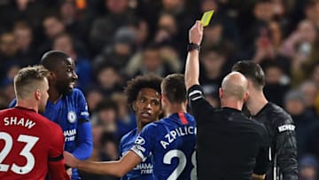 English referee Anthony Taylor shows a yellow card to Chelsea's Brazilian midfielder Willian (C) for simulation during the English Premier League football match between Chelsea and Manchester United at Stamford Bridge in London on February 17, 2020. (Photo by Glyn KIRK / AFP) / RESTRICTED TO EDITORIAL USE. No use with unauthorized audio, video, data, fixture lists, club/league logos or 'live' services. Online in-match use limited to 120 images. An additional 40 images may be used in extra time. No video emulation. Social media in-match use limited to 120 images. An additional 40 images may be used in extra time. No use in betting publications, games or single club/league/player publications. / (Photo by GLYN KIRK/AFP via Getty Images)
