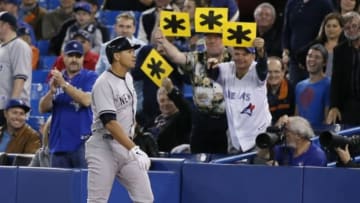Sep 18, 2013; Toronto, Ontario, CAN; Toronto Blue Jays fans hold up asterisk signs as New York Yankees designated hitter Alex Rodriguez (13) comes off the field after flying out in the ninth inning at the Rogers Centre. New York defeated Toronto 4-3. Mandatory Credit: John E. Sokolowski-USA TODAY Sports