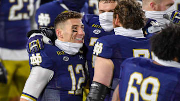 Dec 5, 2020; South Bend, Indiana, USA; Notre Dame Fighting Irish quarterback Ian Book (12) celebrates with offensive lineman Robert Hainsey (72) and offensive lineman Tommy Kraemer (78) after Notre Dame defeated the Syracuse Orange at Notre Dame Stadium. Mandatory Credit: Matt Cashore-USA TODAY Sports