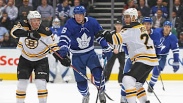 Mitchell Marner #16 of the Toronto Maple Leafs tries to jump between Colby Cave #26 and John Moore #27 of the Boston Bruins during an NHL game at Scotiabank Arena. (Photo by Claus Andersen/Getty Images)