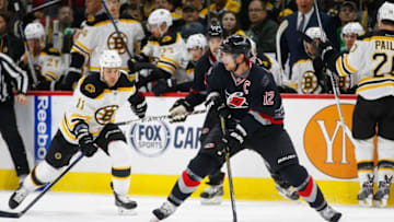 Jan 4, 2015; Raleigh, NC, USA; Carolina Hurricanes forward Eric Staal (12) skates with puck against the Boston Bruins forward Gregory Campbell (11) at PNC Arena. The Carolina Hurricanes defeated the Boston Bruins 2-1 in the shoot out. Mandatory Credit: James Guillory-USA TODAY Sports