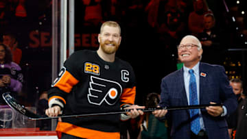 PHILADELPHIA, PENNSYLVANIA - MARCH 17: Claude Giroux #28 of the Philadelphia Flyers is awarded with a commemorative stick by NHL Hall of Fame member and former Flyer Bobby Clarke before a game between the Philadelphia Flyers and the Nashville Predators at Wells Fargo Center on March 17, 2022 in Philadelphia, Pennsylvania. Giroux is playing in his 1,000th-career NHL game. (Photo by Tim Nwachukwu/Getty Images)