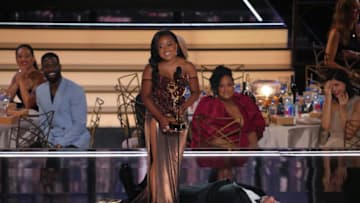 LOS ANGELES, CALIFORNIA - SEPTEMBER 12: (L-R) Quinta Brunson accepts the Outstanding Writing for a Comedy Series award for ‘Abbott Elementary’ from (lying on the stage) onstage during the 74th Primetime Emmys at Microsoft Theater on September 12, 2022 in Los Angeles, California. (Photo by Kevin Mazur/WireImage)