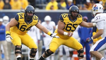 Oct 4, 2014; Morgantown, WV, USA; West Virginia Mountaineers offensive linemen Mark Glowinski (64) and Tyler Orlosky (65) block at the line of scrimmage against the Kansas Jayhawks at Milan Puskar Stadium. West Virginia won 33-14. Mandatory Credit: Charles LeClaire-USA TODAY Sports