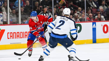 Jan 17, 2023; Montreal, Quebec, CAN; Montreal Canadiens center Nick Suzuki (14) plays the puck against Winnipeg Jets defenseman Dylan DeMelo (2) during the second period at Bell Centre. Mandatory Credit: David Kirouac-USA TODAY Sports