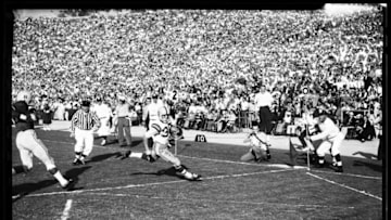 Football -- Ohio State versus Oregon, 1 January 1958. 'Sports'. (Sleeve reads: SP-12374).;Caption slip reads: 'Photographer: Rustan. Date: 1958-01-01. Assignment: Rose Bowl. 59 or 60: Oregon's last pass attempt incomplete. 61: Goal posts down. 23: 16 Ohio intercepts Ore [sic] pass. 24: 84 Ohio takes pass on 24 yd line. 2nd Quarter. 51: 30 Ore [sic] - 22 yds. [sic] 52: 30 Ore - 9 yds. 21: 25 Ore down to 9 yd line. 22: 30 Ore - 1st T.D [sic]. 99: 18 Ohio - returns kick - tackle by 12 and 72 Ore. 100: 22 Ohio to 17 yds, about 30 yds. 27: 18 Ohio with ball. 3rd Q [sic]. 93: 83 pass to Oregon good for 1st down. 94: 40 Ore 1st down. 49: Ore pass incomplete. 50: Ore field goal n.g. R45/46: Flip of coin. Ohio #85 and 36, Ore 30 - 40 - 65 - 50. Referee flipping coin, Tony Srover. 97: 84 Ohio completes pass to 1 yd line. 98: 22 Ohio 1st T.D 95: 40 Ore returns kick'.;Caption slip reads: 'Photographer: Monteverde. Date: 1958-01-01. Assignment: Rose Bowl. 4: #18 25 yard gain to 30 yard line. 3: Ohio touchdown by #22'.. (Photo by Los Angeles Examiner/USC Libraries/Corbis via Getty Images)