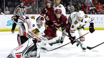 TEMPE, ARIZONA - OCTOBER 30: Logan Cooley #92 of the Arizona Coyotes skates for a loose puck against Connor Murphy #5 of the Chicago Blackhawks during the second period at Mullett Arena on October 30, 2023 in Tempe, Arizona. (Photo by Zac BonDurant/Getty Images)