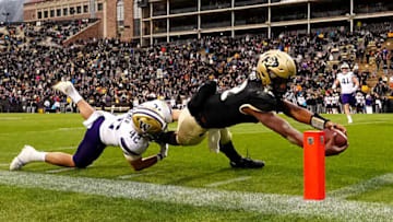Nov 20, 2021; Boulder, Colorado, USA; Colorado Buffaloes quarterback Brendon Lewis (12) scores a touchdown ahead of Washington Huskies linebacker Carson Bruener (42) in the fourth quarter at Folsom Field. Mandatory Credit: Ron Chenoy-USA TODAY Sports