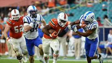 Nov 26, 2016; Miami Gardens, FL, USA; Miami Hurricanes running back Mark Walton (1) stiff arms Duke Blue Devils safety Alonzo Saxton II (21) during the first half at Hard Rock Stadium. Mandatory Credit: Steve Mitchell-USA TODAY Sports
